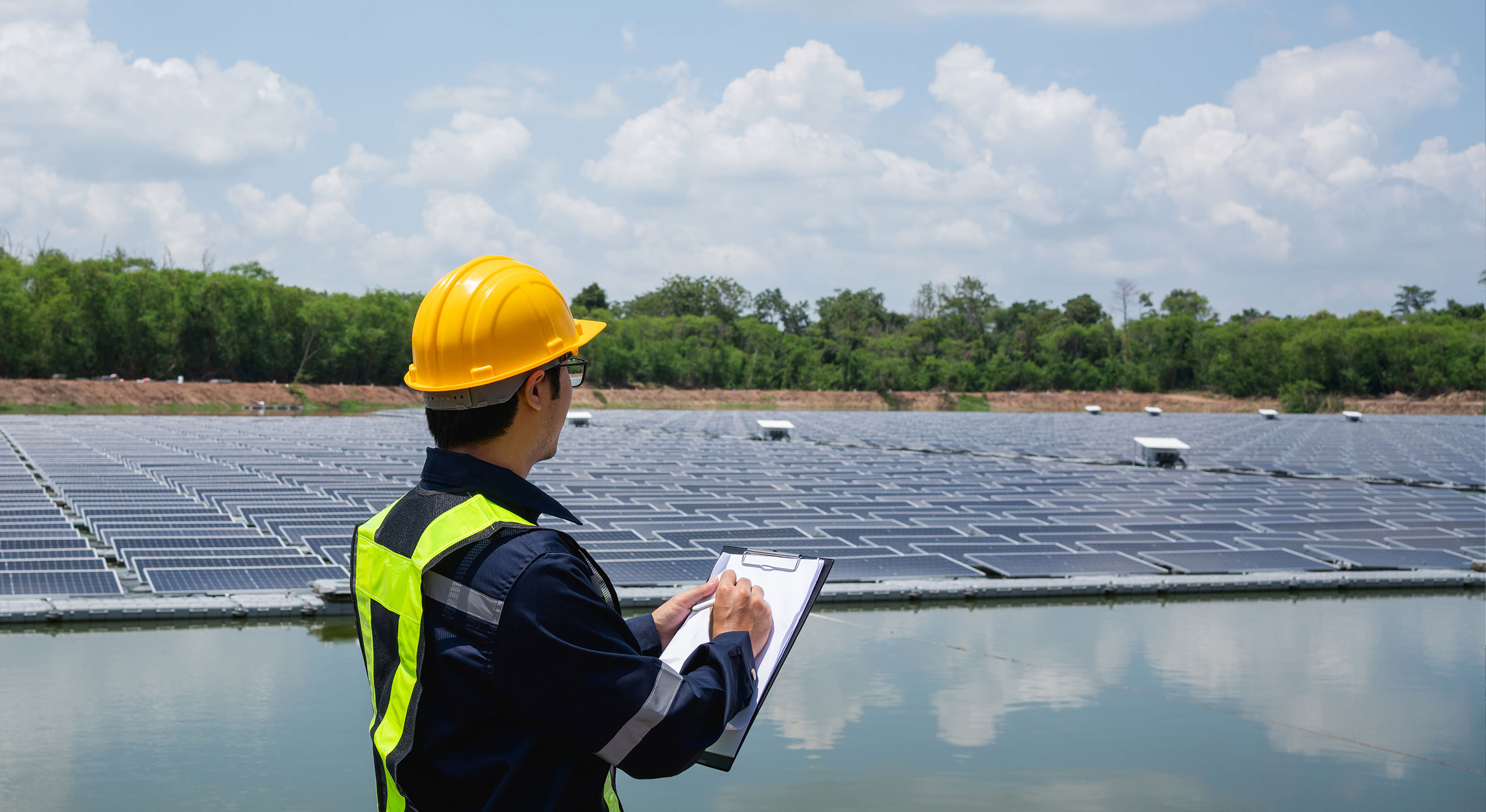 Worker examining solar panels at a solar farm as part of innovative environmental engineering solutions for clean energy and sustainability.