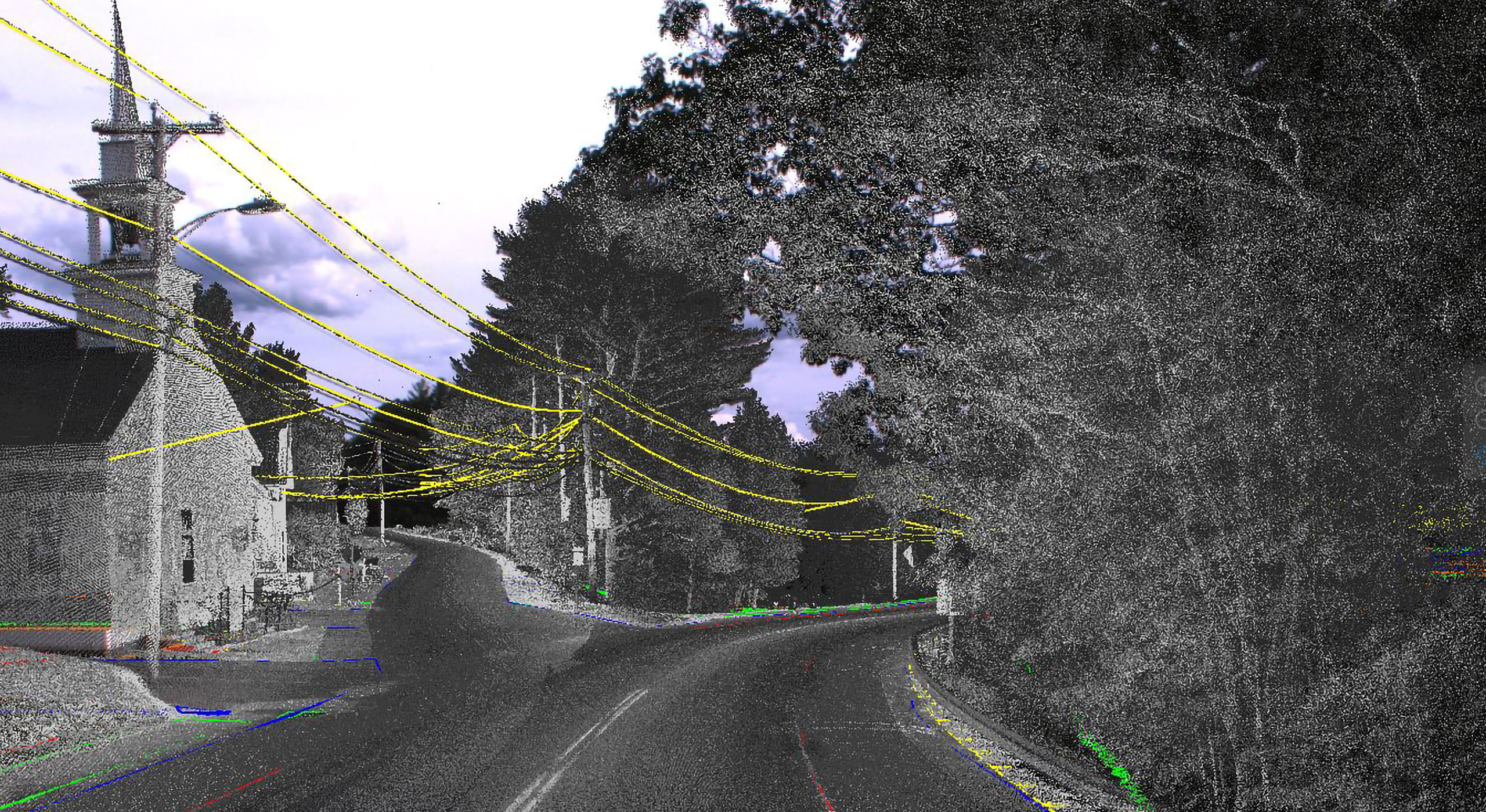 Black and white image of a wooded road with a building, where mobile mapping technology highlights telephone wires and ground features along the route.