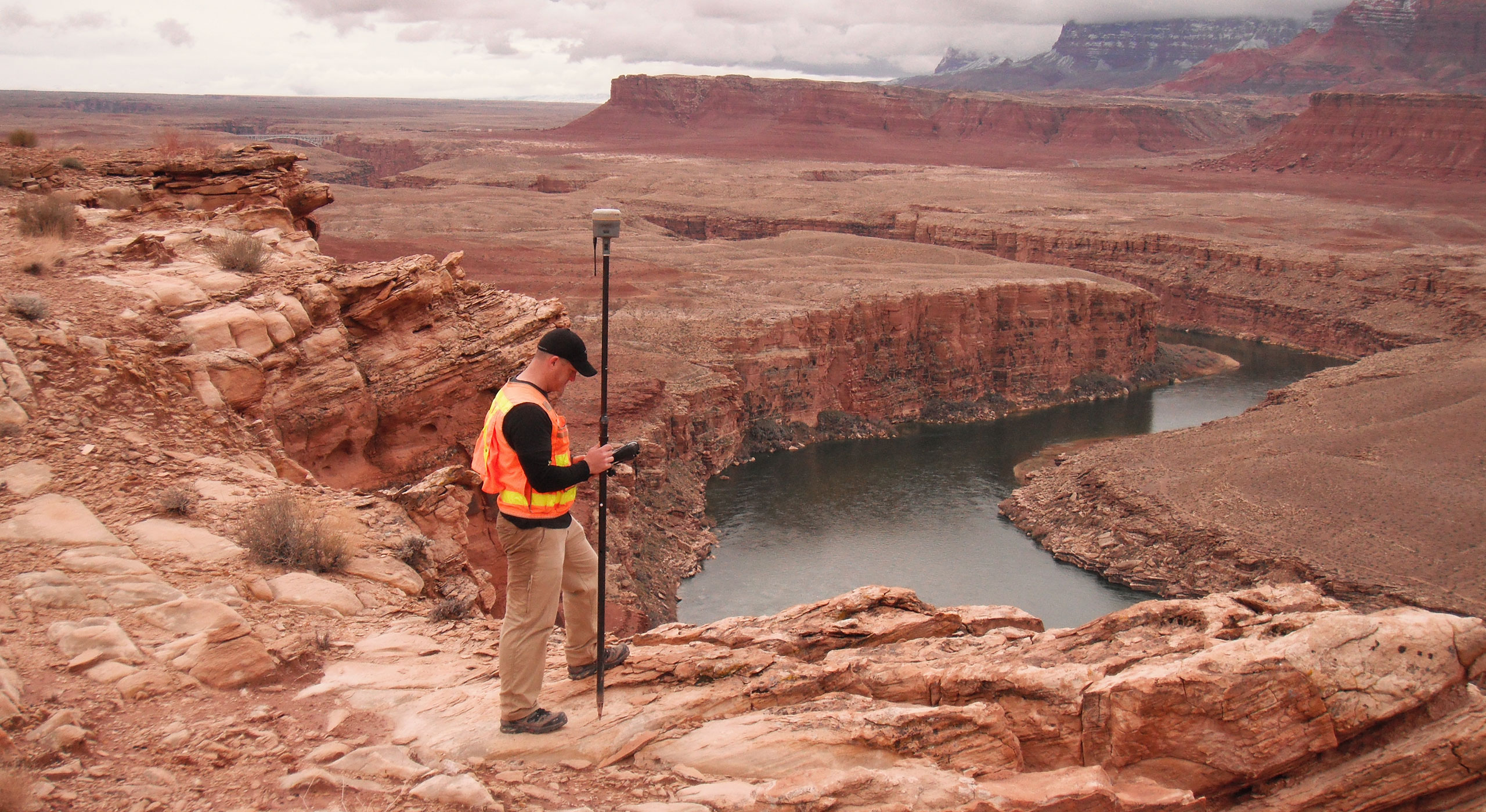 Surveyor using surveying equipment to measure a winding river in Utah.
