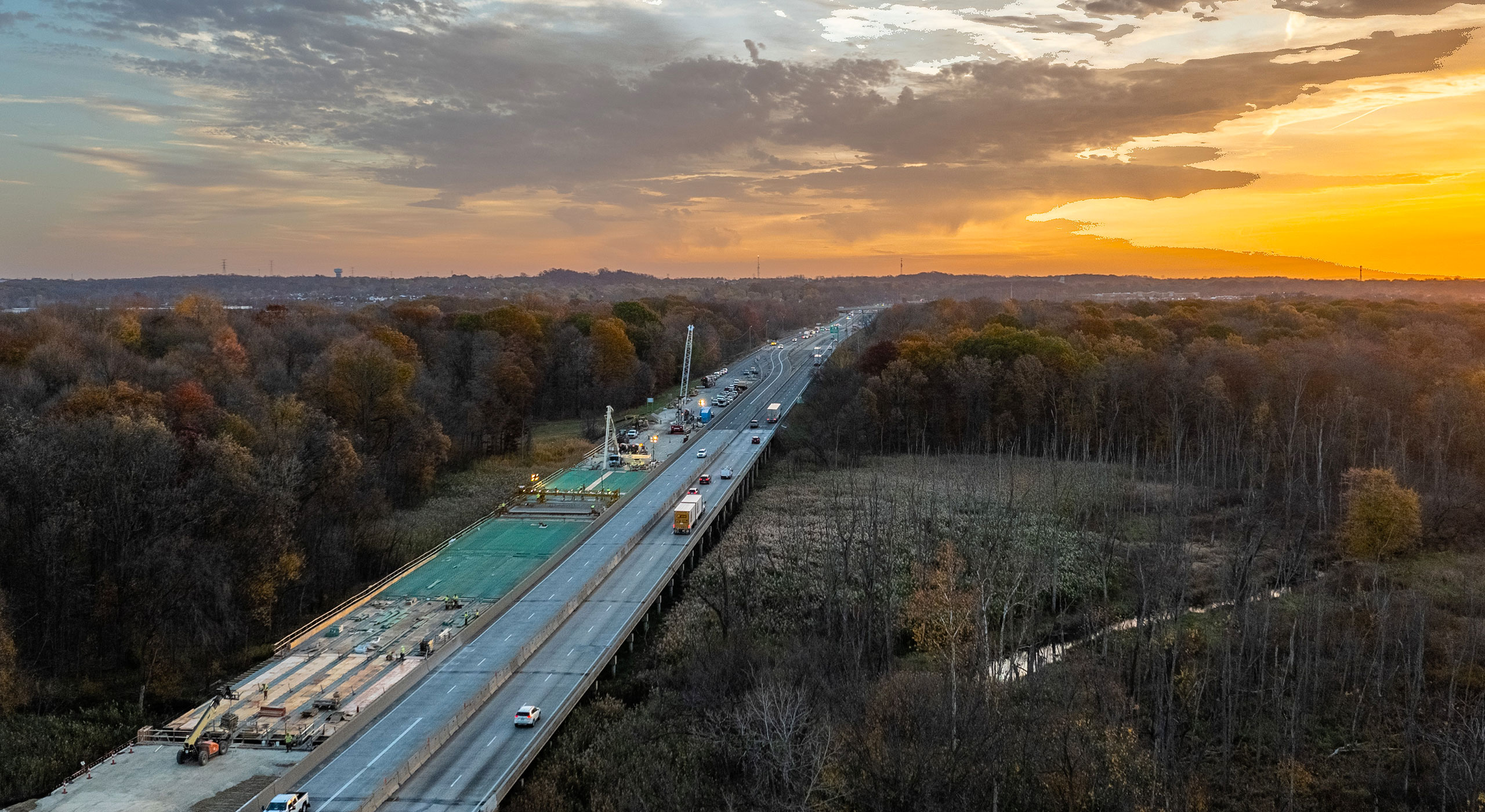 Overhead view of a highway under construction through a dense forest, showcasing transportation engineering in progress.